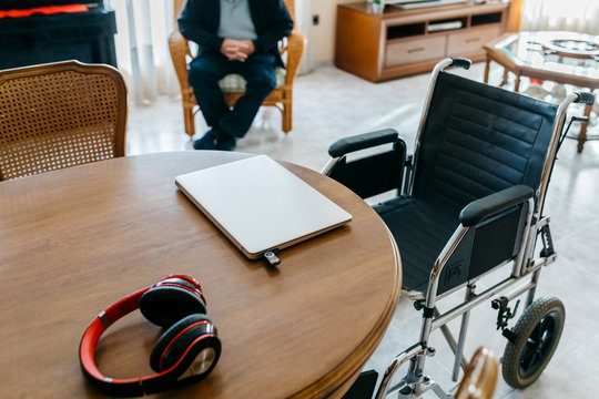 Headphones and laptop with usb-stick on table in living room of senior man