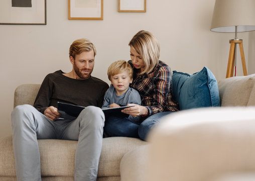 Family looking at book on couch at home