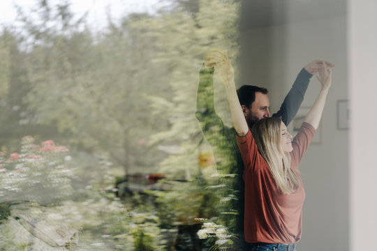 Couple looking out of window, touching hands