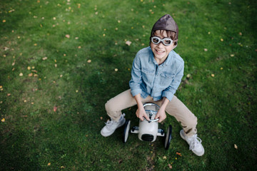 Little boy having fun, riding vintage toy car in the garden
