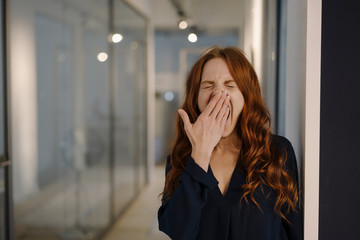 Redheaded woman yawning on office floor