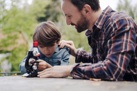 Father and son looking at objects under a microscope
