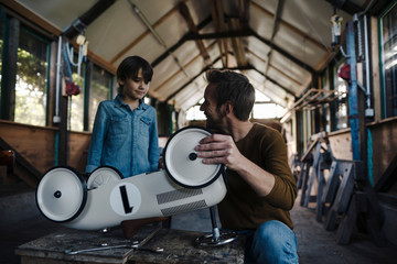 father and son repairing toy car in the barn