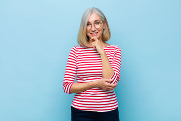 senior or middle age pretty woman looking happy and smiling with hand on chin, wondering or asking a question, comparing options - obrazy, fototapety, plakaty