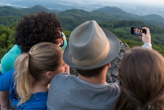 Germany, Siebengebirge, back view of four friends taking a selfie with smartphone on Mount Olivet