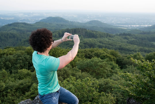 Germany, Siebengebirge, man taking a picture of view with smartphone on Mount Olivet