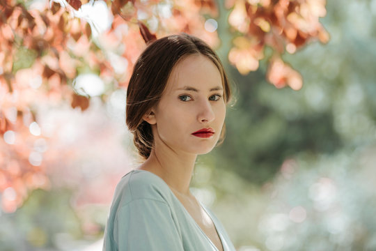 Portrait of young woman with red lips in nature