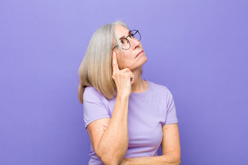senior or middle age pretty woman with a concentrated look, wondering with a doubtful expression, looking up and to the side