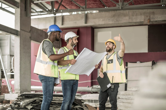 Construction workers discussing building plan in construction site