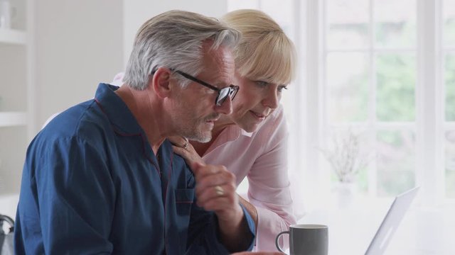 Senior Couple With Man In Wheelchair Looking Up Information About Medication Online Using Laptop