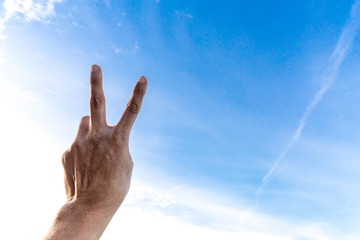 Man's hand showing two fingers up on sky