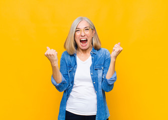senior or middle age pretty woman feeling happy, positive and successful, celebrating victory, achievements or good luck