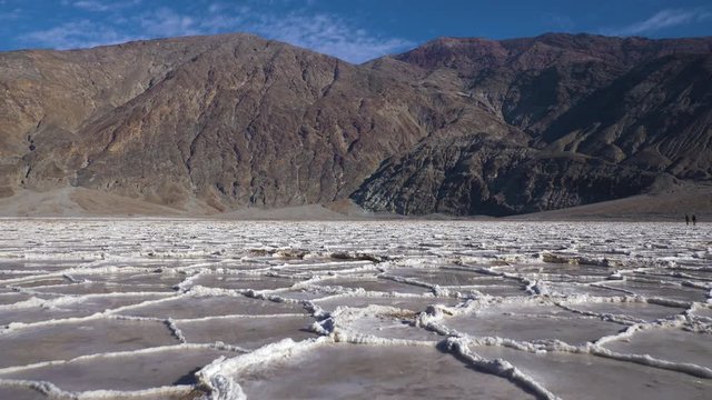Badwater Basin at Sunny Day. Salt Crust Formations with Water and Mountains. Death Valley National Park. California, USA. Aerial View
