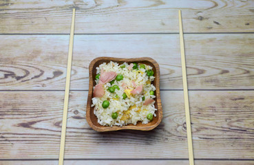 Arroz tres delicias en bol de madera, acompañado de palillos largos