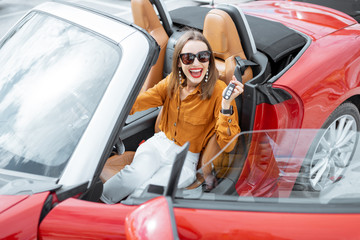Portrait of cheerful woman feeling happy while sitting in the new sports car. Concept of a happy...