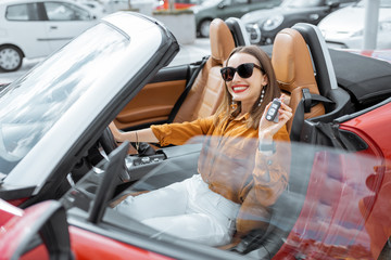 Portrait of cheerful woman feeling happy while sitting in the new sports car. Concept of a happy car buying or renting