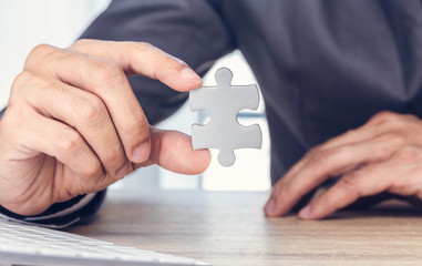 Close up hand of businessman holding two pieces of jigsaw puzzle