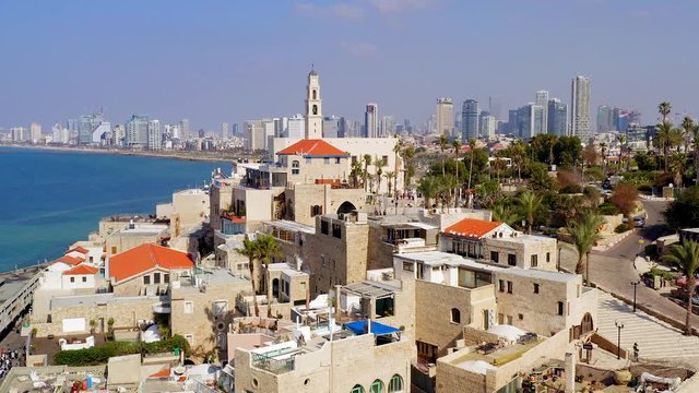 Aerial of Jaffa old city port to Tel Aviv coastline, including close pass and pan left by St. Peter church bell tower heading north to Tel Aviv.