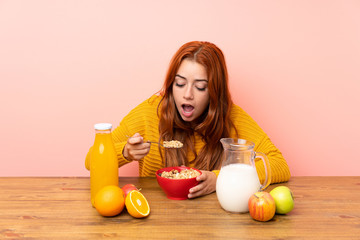 Teenager redhead girl having breakfast in a table