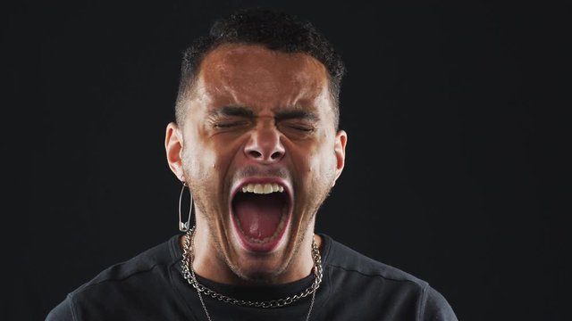 Head And Shoulders Studio Shot Of Angry Man Shouting At Camera In Slow Motion