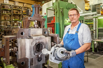 Skilled worker with new piece that was fabricated by a die casting machine