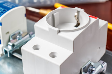 Electric socket in white plastic case installed on DIN rail of electrical panel close-up. Electrical panel assembling
