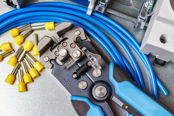 Top view of lying on metal mounting plate wire stripper and blue stranded wire with unused yellow...