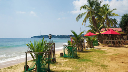 Sandy coast of the ocean. Paradise tropical island beach. Palm trees and sun and people resting