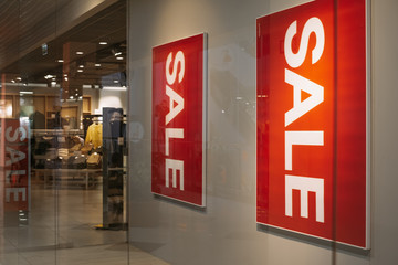 Sale at a clothing store. Red posters with the word Sale at the entrance to the mall