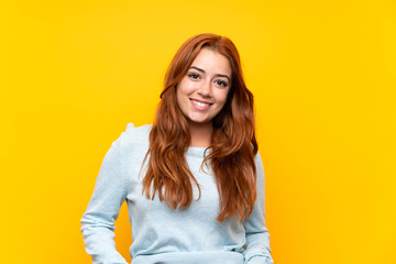 Teenager redhead girl over isolated yellow background laughing