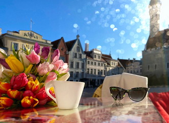 Spring city  Tallinn  Estonia ,street cafe,cup of coffee with Valentine heart on table top and flowers tulip ,blue sky,sunny spring day  sunlight reflection romantic holiday travel to Europe ,Baltic  © Aleksandr