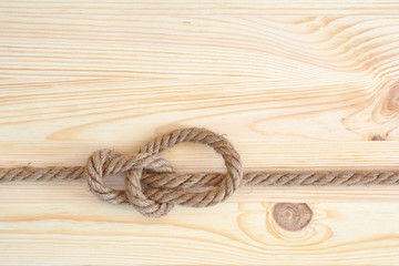 Marine knot used in yachting, bowline knot. Nautical knot on wooden background.