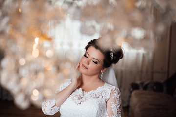 Bride. Wedding. The bride in a short dress with lace in the crown earrings. Wedding makeup,...