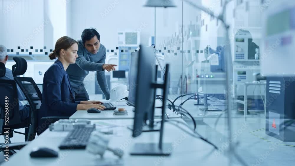 Poster inside factory office: male project supervisor talks to a female industrial engineer who works on co