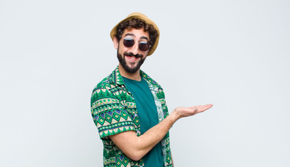 young tourist man smiling cheerfully, feeling happy and showing a concept in copy space with palm...