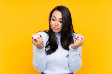 Young Colombian girl over isolated yellow background holding donuts