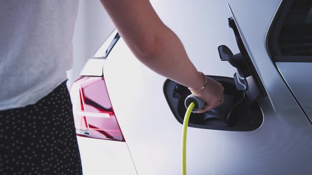 Close Up Of Hand Attaching Power Cable To Environmentally Friendly Zero Emission Electric Car 