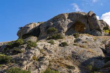 Beautiful view of big mountain with grotto Aeolian Harp on trail Alchak-Kaya. Alchak Cape in south coast of resort Sudak city, Crimea, Russia.