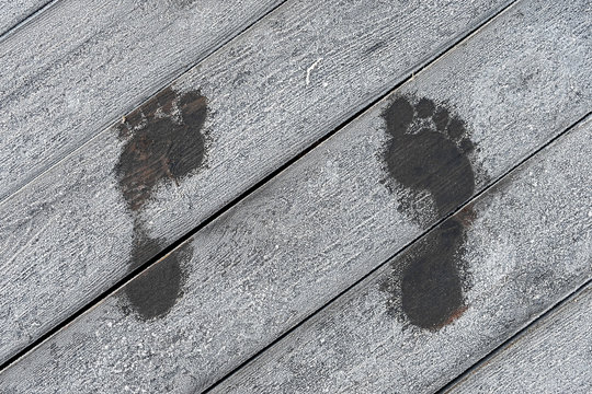 warm trace from bare feet, footprints of a man on a wooden background with frosty fresh morning.