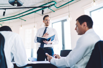 Troubled adult entrepreneur explaining opinion for coworkers during meeting in office