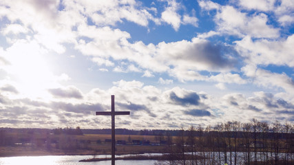 Jesus Christ cross. Easter, resurrection concept. Christian wooden cross on a background with dramatic sky and countryside landscape.