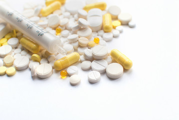 A bunch of yellow and white tablets, pills isolated on a white background with syringe. close up. Selective focus. Health day. Copyspace