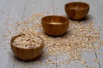 Oats with a wooden cup on white wood background
