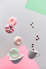 St. Valentine concept, levitation of doughnuts above heart shaped bowl. Coffee beans fly in espresso cup. Creative split surreal food background in pink, green mint and light grey colors.