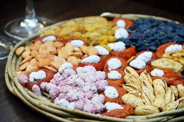Dried fruits, nuts, healthy oriental sweets on a wicker basket. Beautiful textiles