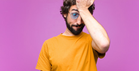 young crazy cool man raising palm to forehead thinking oops, after making a stupid mistake or...