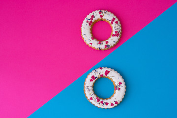 Creative layout made of glazed ring shape rolls, bagels with colorful hearts. Flat lay. Nature concept. Conceptual greeting card. Colorful spring background, space for text. Trendy Decorative Design.