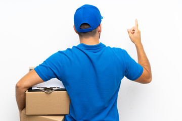 Fototapeta na wymiar Delivery man over isolated white background pointing back with the index finger