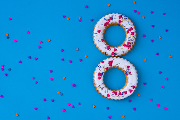 Creative layout made of glazed ring shape rolls, bagels with colorful hearts. Flat lay. Nature concept. Conceptual greeting card. Colorful spring background, space for text. Trendy Decorative Design.