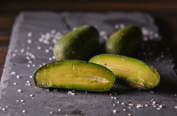 closeup of small avocado isolated in a table with salt. dark food.